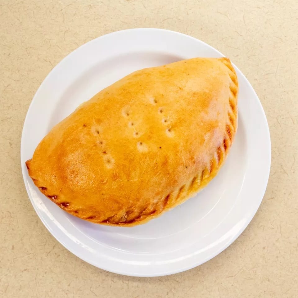Golden brown calzone with crimped edges and small vents, served on a white plate.